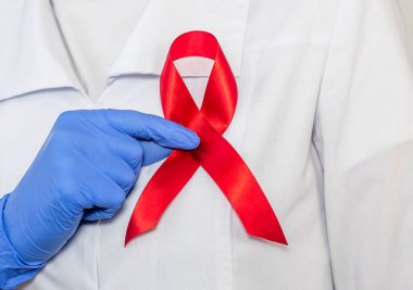 AIDS ve HIV dünya desteği için kırmızı kurdele, yakın çekim. Kadın doktorun eli..