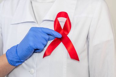 AIDS ve HIV dünya desteği için kırmızı kurdele, yakın çekim. Kadın doktorun eli..