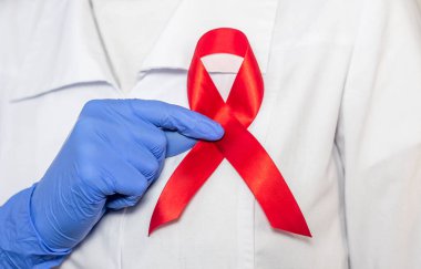 AIDS ve HIV dünya desteği için kırmızı kurdele, yakın çekim. Kadın doktorun eli..
