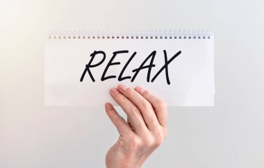 Rahat ol. Beyaz kağıt üzerinde el yazısıyla yazılmış yazı erkek ellerinde, tatillerde ve dinlenme konseptinde.