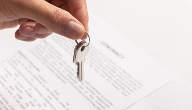 Yakın plan, elinde kontratı olan yeni bir daireden anahtar tutan bir adam..