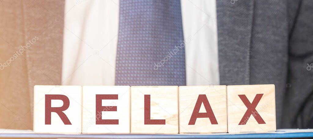 Relax word on cube blocks with blurred businessman suit, dicrease stress concept