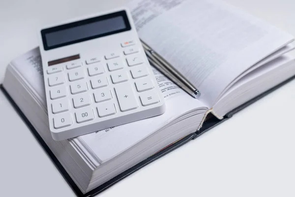 Business financial or tax law concept. Calculator and open book on table.