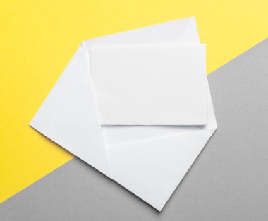 Sarı ve gri arka planda zarfın içinde boş kağıt var. Model.