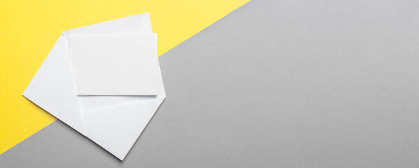 Blank paper card in envelope on yellow anf gray background. Mock up. Banner with copy space