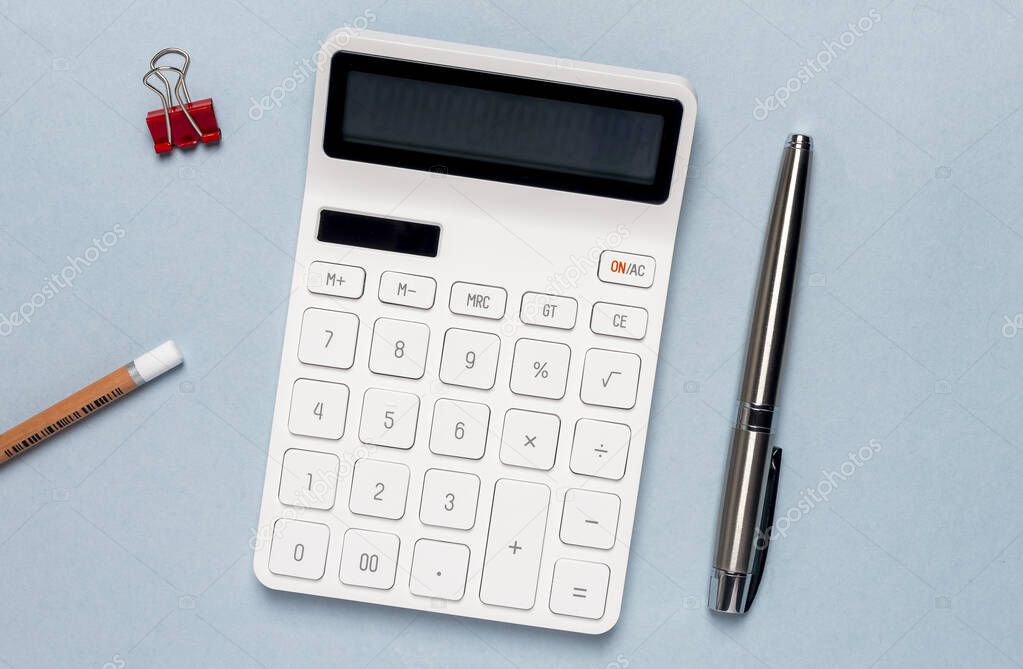 Calculator on blue table with pen. Workplace of accountant.