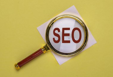 Moda sarı renk üzerinden büyüteçten geçen SEO sözcük kısaltması.