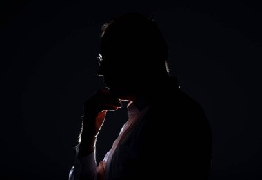 Arkadan ışıklandırmalı ve gözlüklü bir erkek silueti..