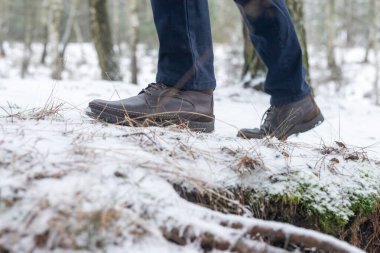 Karlı yolda erkek botları, yan görüş. Kış ormanlarında yürüyen ya da gezinen bacaklar..