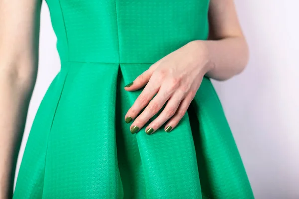 Mão feminina com unhas de cor verde em vestido verde — Fotografia de Stock