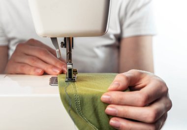 Dikiş makinesinin iğnesinin altındaki kadın ellerini kapatın. Yavaş moda konsepti.
