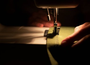 Dikiş makinesinin iğnesinin altındaki kadın ellerini kapatın. Yavaş moda konsepti.