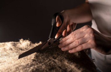 Terzinin kadın eli, doğal organik keten kumaşı makasla kesiyor..