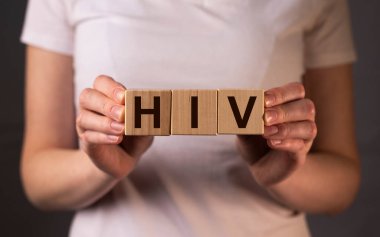 HIV kısaltması, dişi ellerindeki tahta küplere yazılmış yazı..