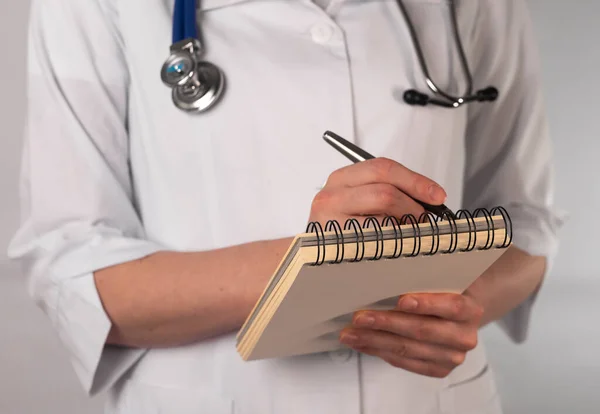 Female doctor holding notepad and writing prescription.