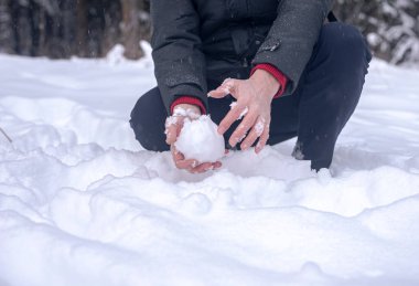 Çıplak erkek eller ormanda kardan kartopu yapar ya da şekil verir. Yaklaş..