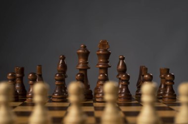 Satranç tahtasındaki siyah satranç figürlerine karşı bulanık beyaz piyonlar.