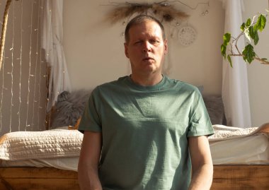 Yoga, meditasyon ve nefes kontrolü yapan bir adam, rahat bir yatak odasında meditasyon yapıyor..