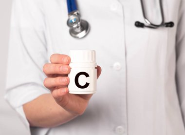 Doktor elinde beyaz şişede C vitamini.