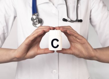 Doktor elinde beyaz şişede C vitamini.