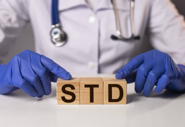 Doktorun elindeki tahta küplere yazılmış STD kısaltması..