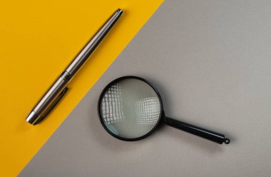 Gri ve sarı arkaplanda büyüteç ve kalem.