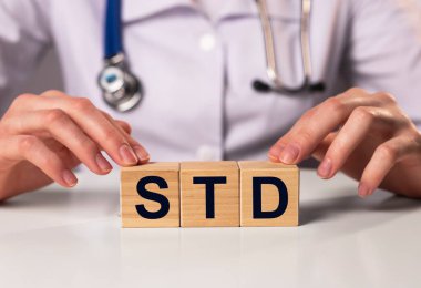 Doktorun elindeki tahta küplere yazılmış STD kısaltması.