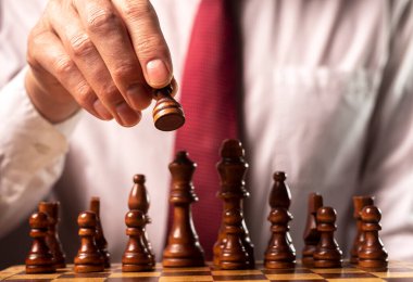 Ticari mali strateji kavramı. İş adamı karar veriyor ve satranç taşını diğer satranç figürleri üzerinde taşıyor.