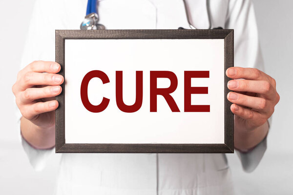 Word cure in doctor hands on paper. Medical concept