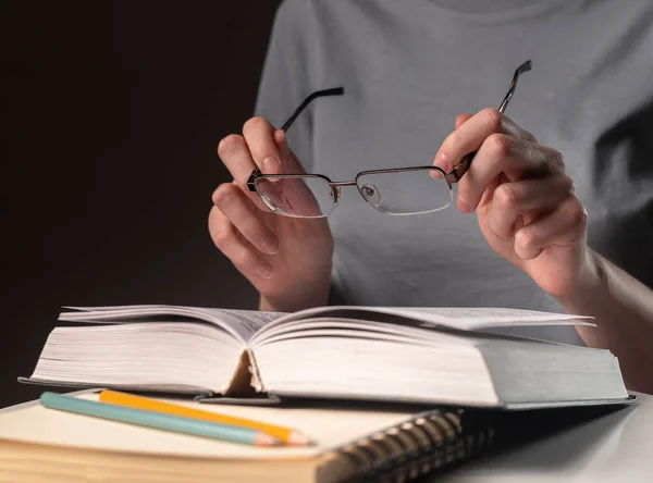 女性学生の手を閉じて、眼鏡や本や教科書を保持し、情報を検索し、夜に読書 — ストック写真