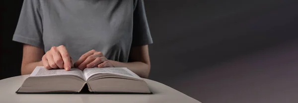 Female student hands close up, pointing on text in book or textbook, searching for information and reading at night. Banner with copy space