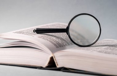 Sayfaları çevirerek ve büyüterek kitabı kapat. Masanın üzerinde sert bir kapakla ders kitabı. Öğrenim ve araştırma konsepti