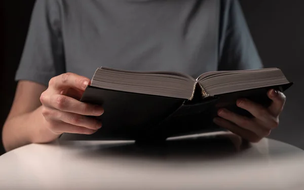 Les mains féminines ferment, tenant et lisant le livre ou le manuel en couverture rigide la nuit — Photo