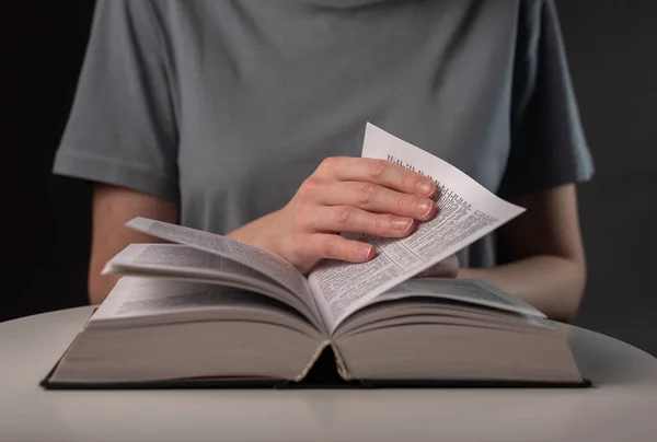 Female student hands close up, turning pages of thick book, searching for information and reading
