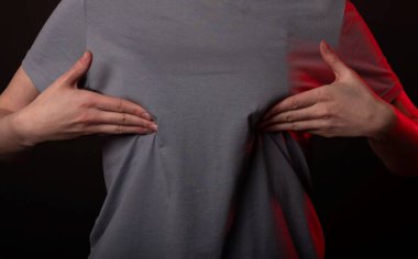 Bir kadın memesine dokunuyor, muayene ediyor. Kendini tarama, inceleme ve tespit