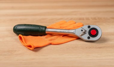 Priz mandal saplı bir eldiven. Endüstriyel metal alet, ahşap zemine yakın.