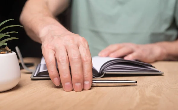 Mãos masculinas começando a planejar seu dia, escrevendo seu cronograma em organizador, diário, planejador. Homem tomando caneta na mesa de madeira — Fotografia de Stock