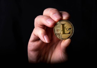 Parlak litekoin altın LTC madeni para erkek eli siyah arkaplan üzerinde.