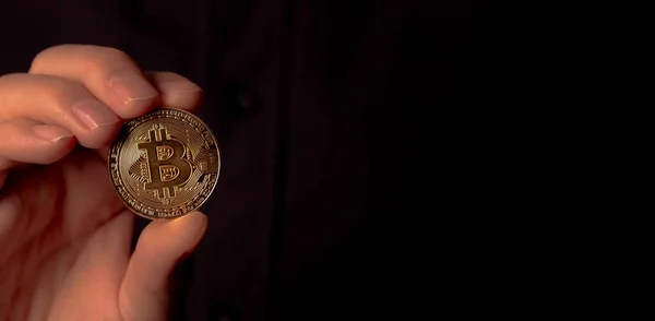 Glänsande bitcoin BTC gyllene mynt i manlig hand över svart bakgrund. Lite kryptovaluta. Banner med kopieringsutrymme för text — Stockfoto