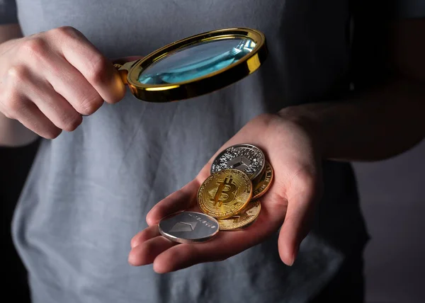 Parlak altın ve gümüş paralar, büyüteç ile kadın avucunda şifrelenmiş para. Bitcoin ve diğer kripto para yığınları