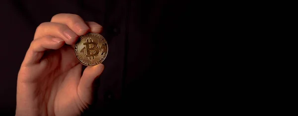 Shining bitcoin BTC golden coin in male hand over black background. Bit crypto currency banner with room for text — Stockfoto