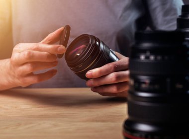 Fotoğrafçının elleri, dijital kamera lenslerini kapatıyor. Tahta masa, işyeri, kapat.