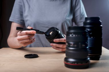 Modern dijital kamera lenslerini profesyonel fırça ya da fırçayla temizleyip tozu temizleyen kadın ellerini kapat