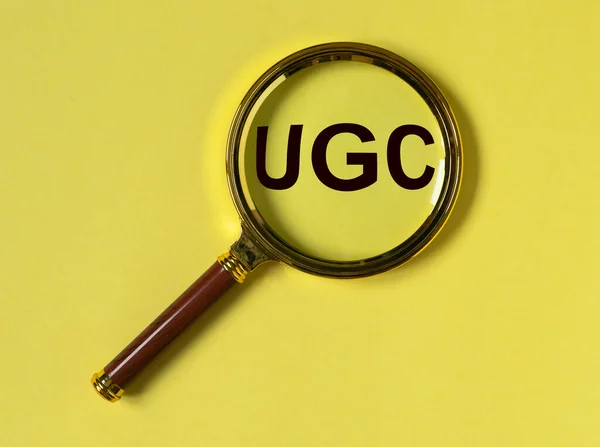 带有loupe的黄色背景社交媒体UGS或用户生成的内容首字母缩写 — 图库照片
