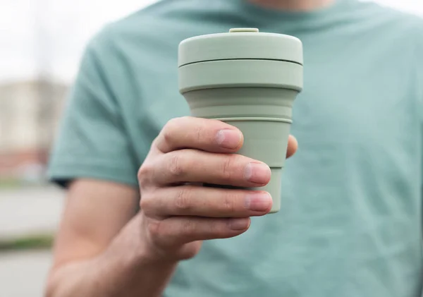 Copo reutilizável Eco para tomar café ou chá. Mão masculina com caneca de silício sustentável. Vida de pessoa ecológica — Fotografia de Stock