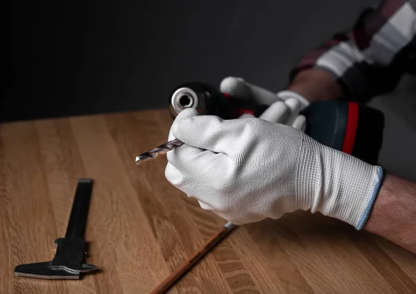 Närbild man hand i handskar som håller metall auger och sätta den på borr verktyg över trä skrivbord — Stockfoto