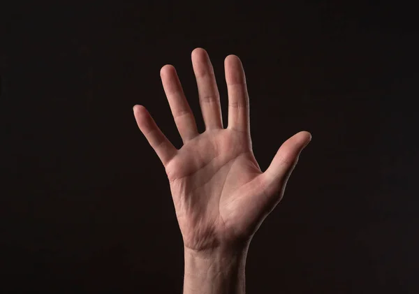 Man handflatan gestikulerar hallå eller hej över svart bakgrund. Hälsningsgest — Stockfoto