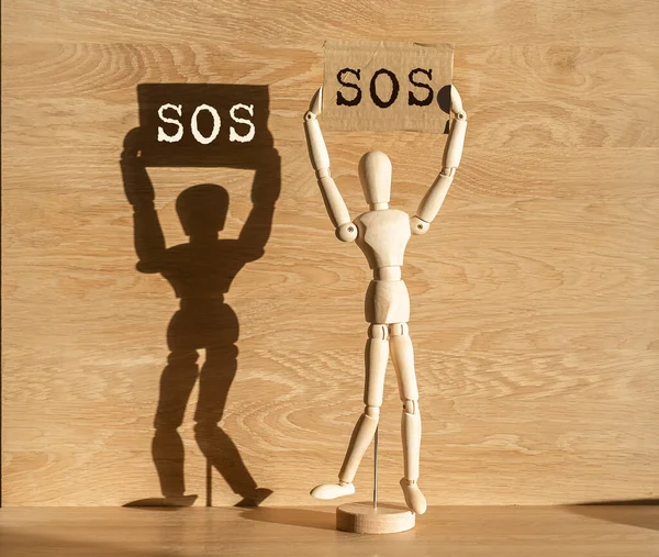 Wooden abstract person holding SOS placard in hands. Activism and call for help concept