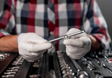 Beyaz eldivenli erkek eller, açık alet çantasının üzerinde. Araba tamiri için ingiliz anahtarı var. Kapatın.