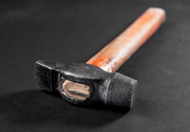 Metal başlı eski bir çekiç ve siyah arka planda ahşap saplı.